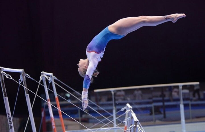 Гимнастка исполняет сложный элемент